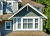 Exterior view of a house with gray siding, green shingles, and 50% VLT static cling window tint