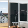 Modern room with large window with 5% VLT static cling window tint over a city view, featuring a floor lamp, table, and sofa.